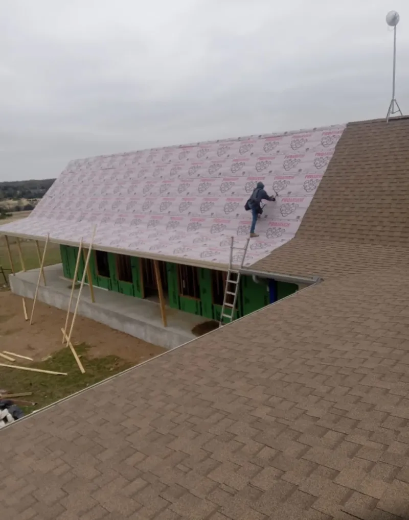 Worker preparing underlayment for a metal roof installation in Bend